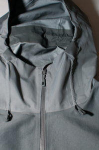 Justeringen för luvan samt blixtlåset. Under det svarta partiet sitter dragskon för corden.